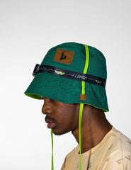 Green bucket hat with a brand logo and strap worn by a person on a white background