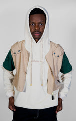 Person wearing a beige and green jacket with a white hoodie on a plain background