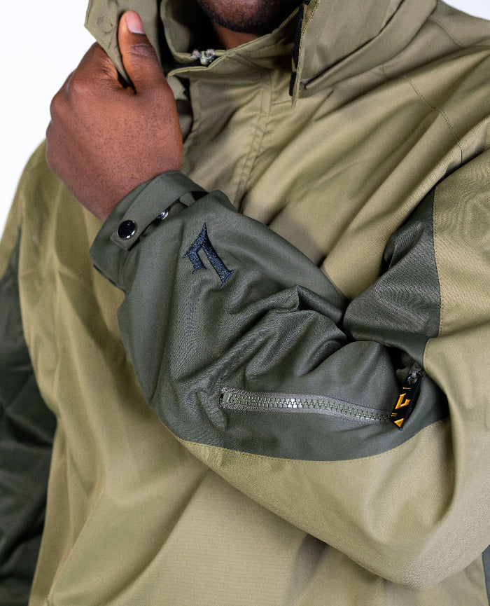 Close-up of a person wearing a green jacket with a brand logo on the sleeve.