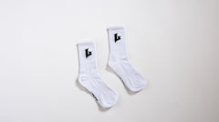 Pair of white socks with black logo on a light gray background