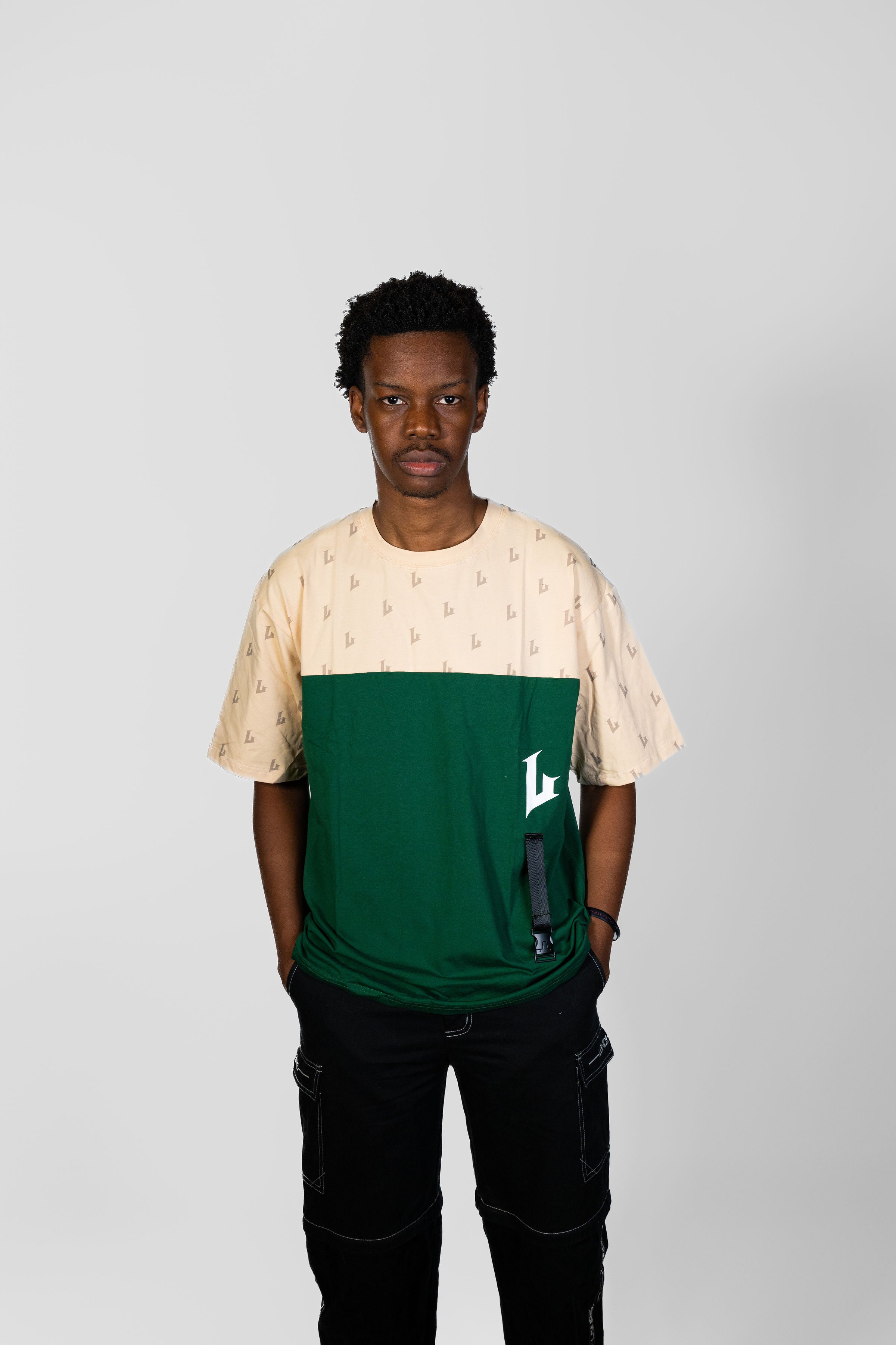 Person wearing a green and beige shirt with a logo on a gray background