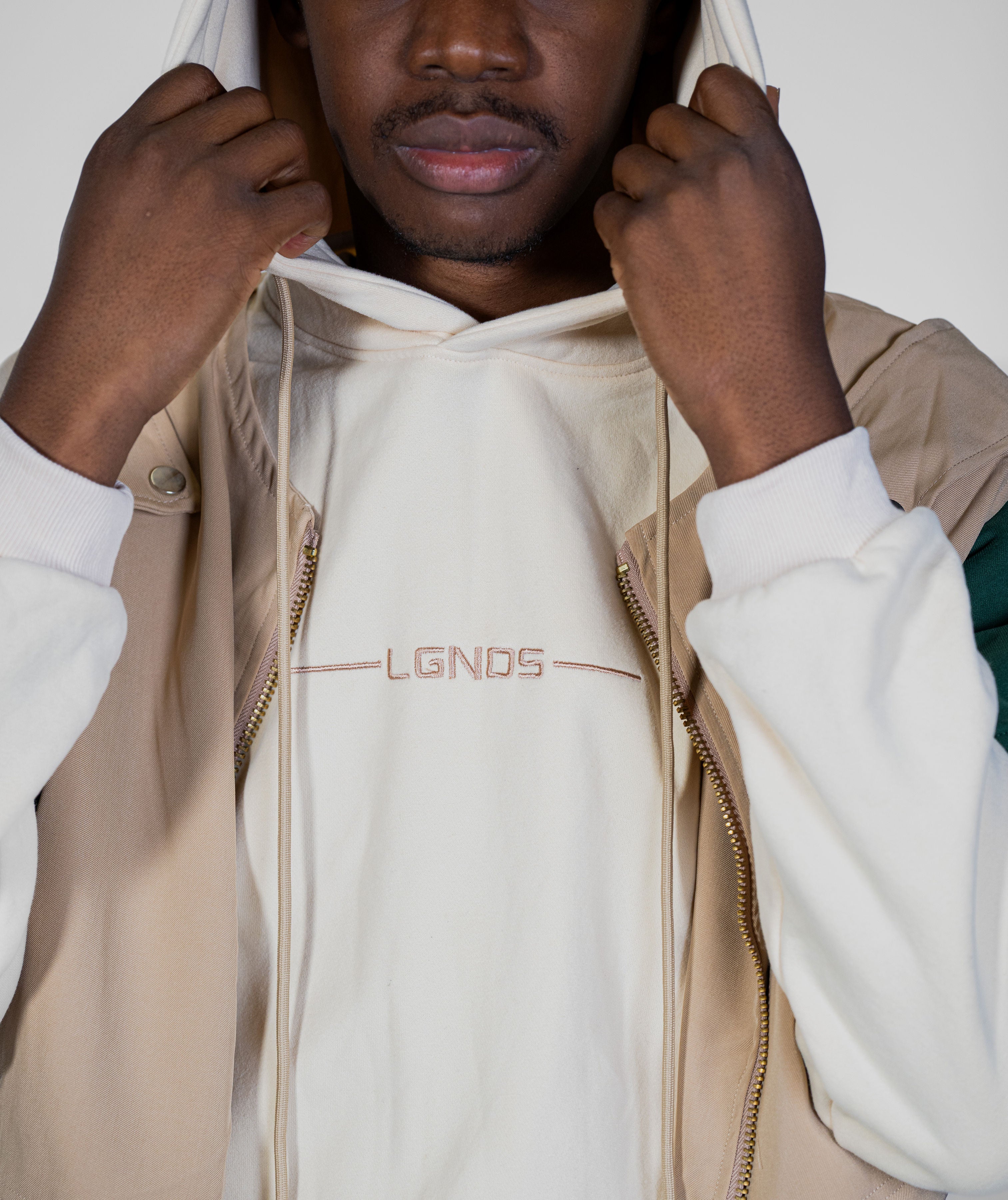 Person wearing a beige and white jacket with 'LGNDS' branding on a light background