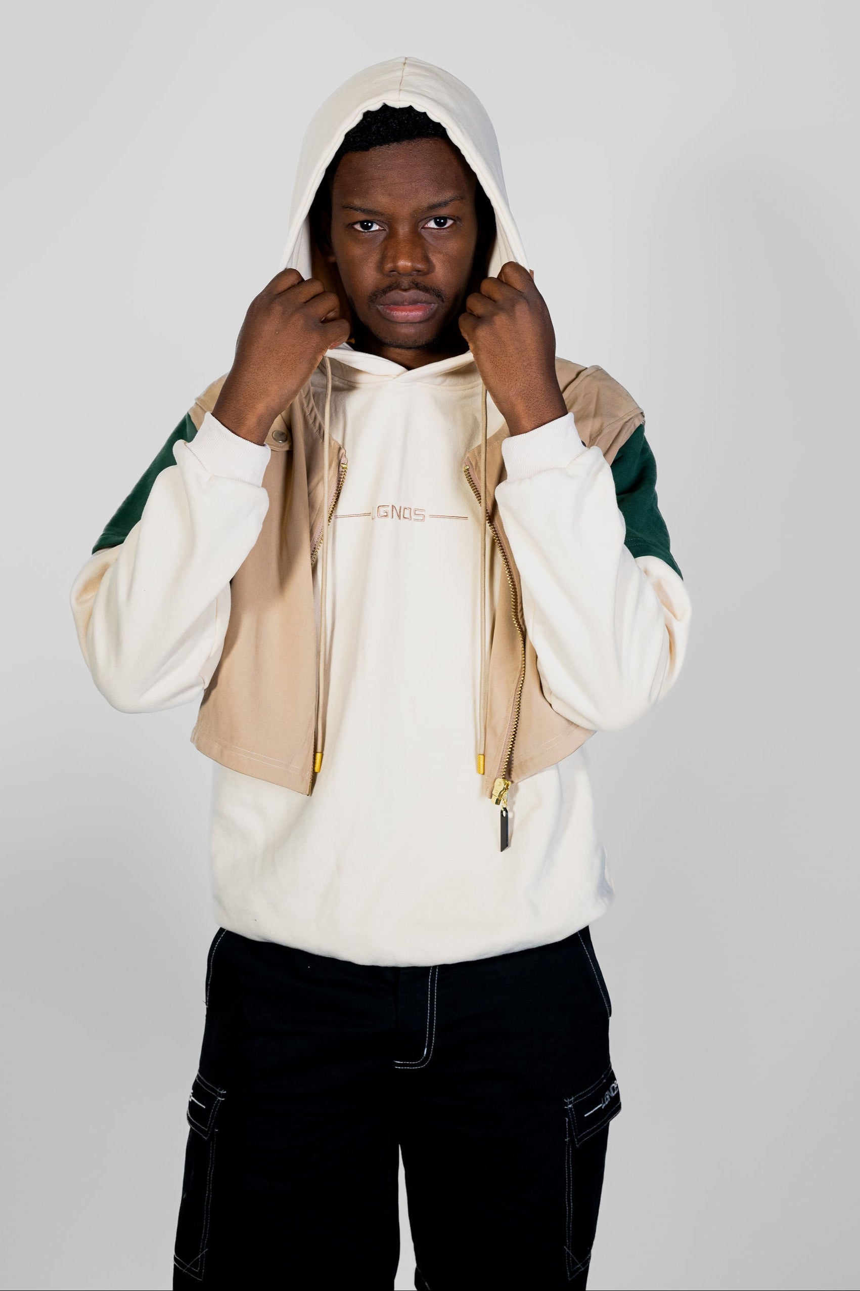 Person wearing a beige and green hoodie on a plain background