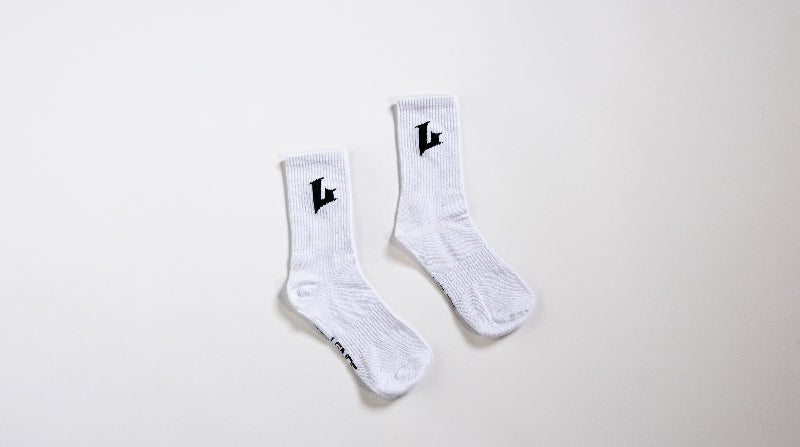 Pair of white socks with black logo on a light gray background